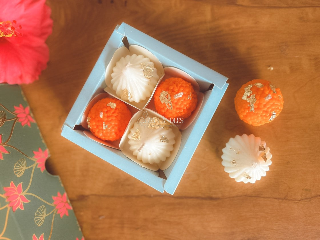 Ganpati festive gift set featuring handcrafted 100% soy wax ladoo candles and modak candles with gold foil, in a lotus-print decorative box for pooja décor and gifting.