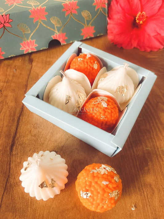 Ganpati festive gift set featuring handcrafted 100% soy wax ladoo candles and modak candles with gold foil, in a lotus-print decorative box for pooja décor and gifting.